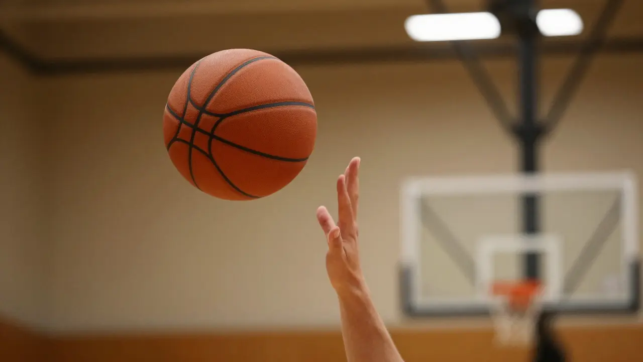 Basketbalový míč letící vysokým obloukem směrem k koši