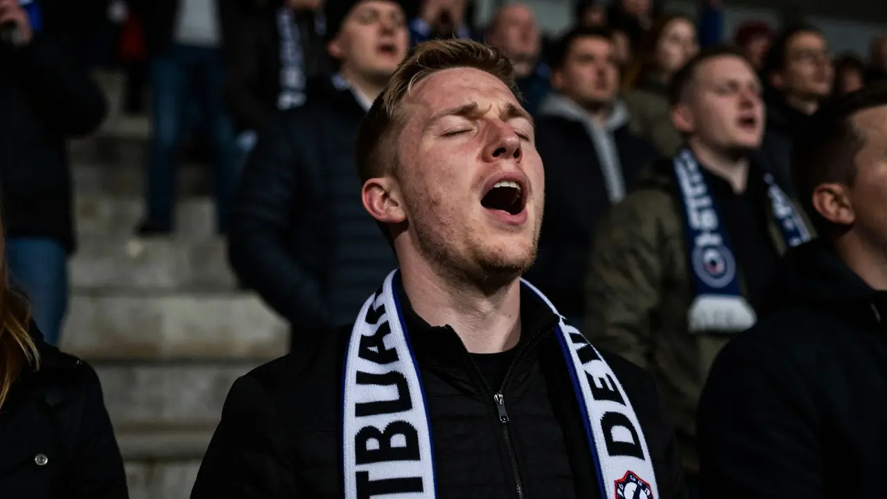 Zblízka zachycený vášnivý fanoušek Slovana Liberec zpívající na tribuně