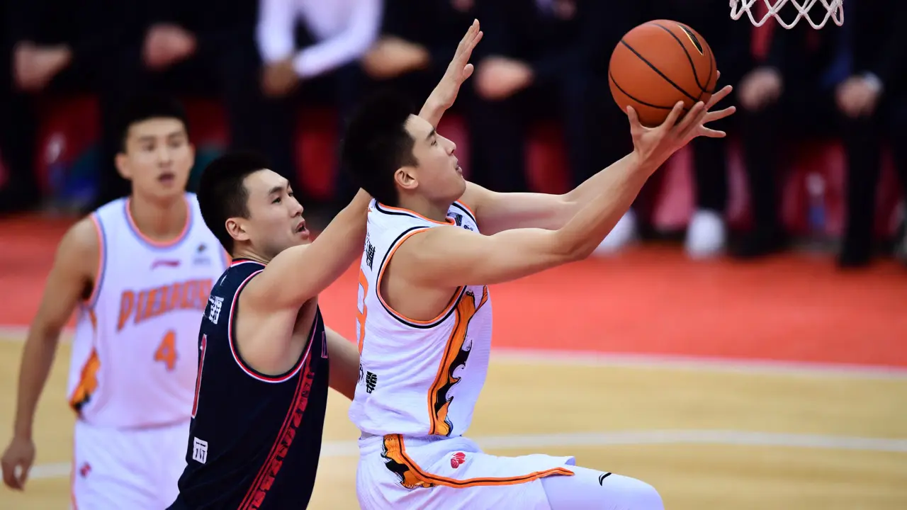 Útočník v ojnici provádí rychlý pohyb při obranném tlaku soupeře během basketbalového zápasu.
